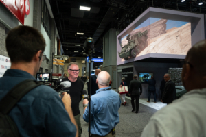 Dave being interviewed by Straight Arrow News at the AUSA exhibition, with a military vehicle display in the background.